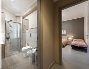 a bathroom with a shower toilet and a bed at Aura Deluxe Apartments in Syracuse +18 photos