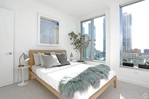 a white bedroom with a bed with a green blanket on it at Spera in San Francisco