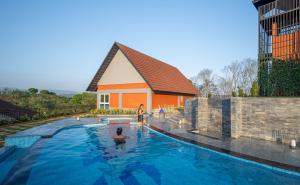 a woman in a swimming pool in front of a building at Hill Seasons Resorts and SPA in Tindummal