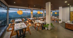 a restaurant with tables and chairs and windows at Hill Seasons Resorts and SPA in Tindummal