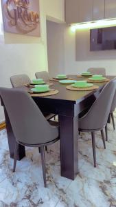 a dining room table with chairs and a table with green plates at Q2Shortlet Apartment in Isheri-Olofin +9 photos