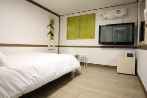 a bedroom with a bed and a flat screen tv at Hangeul Guesthouse in Seoul