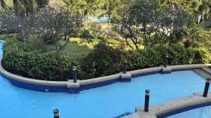 a swimming pool in a resort with trees and bushes at 1 BR Loft Condo in Cha-Am in Cha Am