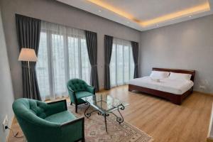 a bedroom with a bed and two chairs and a table at Villa Alam Klang managed by Bella Vista Hotels & Resorts in Klang