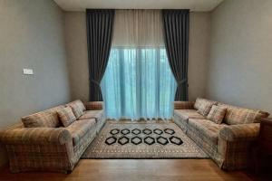 a living room with two couches in front of a window at Villa Alam Klang managed by Bella Vista Hotels & Resorts in Klang