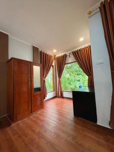 an empty living room with wooden floors and large windows at Asim Paris Guesthouse & jungle trekking in Bukit Lawang