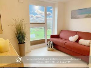 a living room with a red couch and a window at Ferienwohnung de Lark Penthouse mit Nordseeblick in Dorum-Neufeld