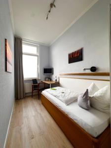 a bedroom with a bed and a desk and a window at Hotel Haus Margarete am Meer in Norderney