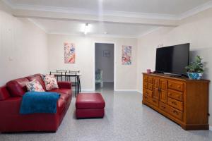 a living room with a couch and a television on a dresser at Kookaburra Guesthouse in Coffs Harbour