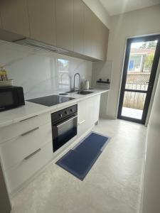 a white kitchen with a sink and a stove at Modern Private 2BR Unit in Takapuna in Auckland