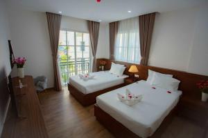 a hotel room with two beds and a balcony at Hotel Kim Thái in Phú Quốc
