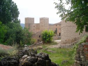 un antiguo castillo con una pared de piedra y árboles en Casa Santiuste, en Corduente