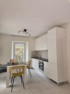 a kitchen with white cabinets and a table and chairs at Casa Chiara in Cavergno