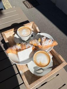 ein Teller mit Essen, zwei Tassen Kaffee und Gebäck in der Unterkunft Evy’s Rooms in La Spezia