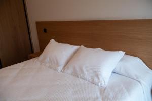 a white bed with a wooden headboard and two pillows at Casa Avó Libânia in Murça