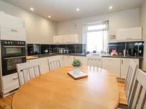 a kitchen with a wooden table and a kitchen with white cabinets at Corner Cottage in Buxton