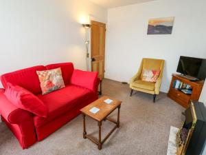 a living room with a red couch and a chair at Bay View in Swanage