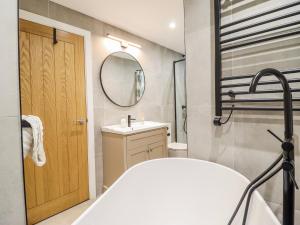 a bathroom with a tub and a sink and a mirror at Hafod Y Bryn in Harlech +41 photos