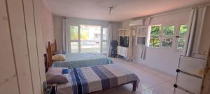 a bedroom with a bed and a tv and two windows at Recanto do Pontal in Japaratinga