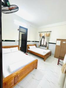 a bedroom with two beds and a chair at Homestay Mai Trường Cù Lao Chàm in Tân Hiệp