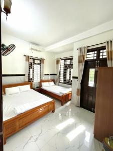 a bedroom with two beds and two windows at Homestay Mai Trường Cù Lao Chàm in Tân Hiệp
