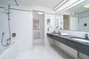 a white bathroom with a sink and a shower at elaya hotel noerdlingen, Trademark by Wyndham in Nördlingen