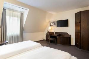 a hotel room with a desk and a bed at elaya hotel noerdlingen, Trademark by Wyndham in Nördlingen