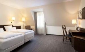 a hotel room with two beds and a desk at elaya hotel noerdlingen, Trademark by Wyndham in Nördlingen