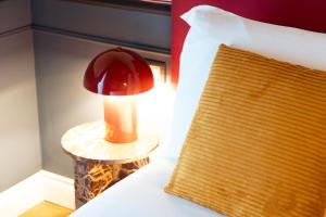 a red lamp on a table next to a bed at JOIVY Together Florence Secret Nest in Florence +38 photos