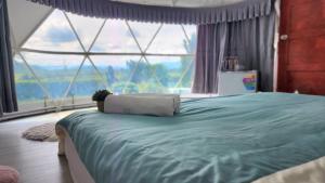 a bedroom with a large bed with a large window at Phunapat camping Dome in Ban Song Phi Nong