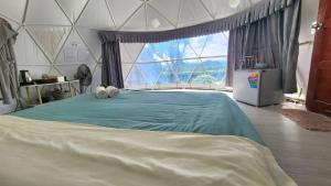 a bedroom with a large bed with a large window at Phunapat camping Dome in Ban Song Phi Nong