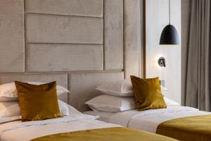 two beds with yellow pillows in a room at East Plaza Hotel in Sofia +83 photos