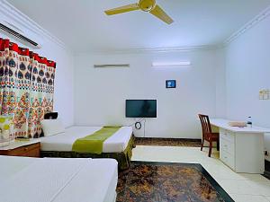 a hotel room with two beds and a tv at Maya Eco Guest House in Dhaka