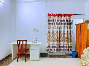 a desk and a chair in a room with a curtain at Maya Eco Guest House in Dhaka