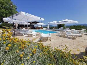 a swimming pool with white chairs and umbrellas at Хотел Магура in Rabisha