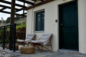 two chairs sitting on a porch with a door at Αλώνι - Aloni in Angathiás