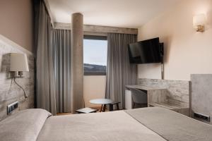 a hotel room with a bed and a desk and a television at Hotel Palau de Girona in Sant Julià De Ramis