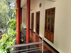 a balcony with red columns and a wooden door at Villa in Chengannur in Māvelikara +2 photos