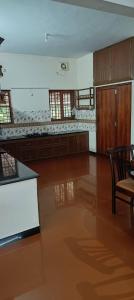 a large empty kitchen with a table and chairs at Villa in Chengannur in Māvelikara