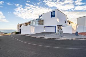 a white house with the ocean in the background at The Lighthouse in Cape Town