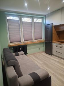 a room with a bed and a refrigerator and windows at K&H Tarnów Centrum in Tarnów