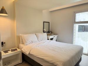 a bedroom with a white bed with a window at LeBlanc Hotel in Antipolo +4 photos