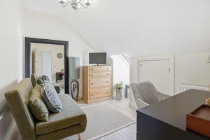 a living room with a couch and a tv at The Luxe Pool House, Westoning in Westoning