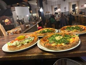 four pizzas sitting on plates on a wooden table at Gesundaberget Lodge & Parstugor in Gesunda