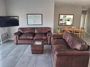a living room with a brown leather couch and a table at SeeSkattie in St. Helena Bay