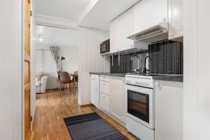 a kitchen with white cabinets and a stove top oven at Apartment close to the mountain in Svolvær