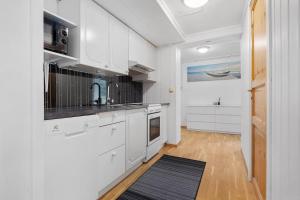 a kitchen with white cabinets and a black counter top at Apartment close to the mountain in Svolvær +13 photos