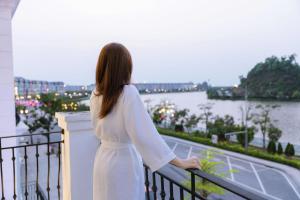 a woman standing on a balcony looking out at the water at The Muse Hotel 3 in Ðố Sơn