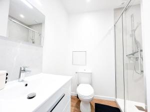 a white bathroom with a toilet and a shower at L'Orchidée Marine, T2, 100m plage et du commando in Saint-Nazaire