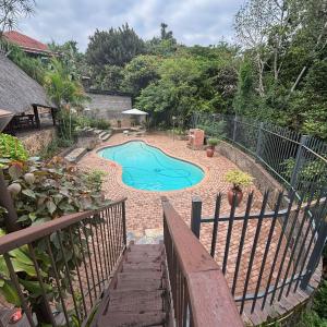 a swimming pool in a yard with a fence at The Rock & Root Guesthouse Self Catering in Nelspruit